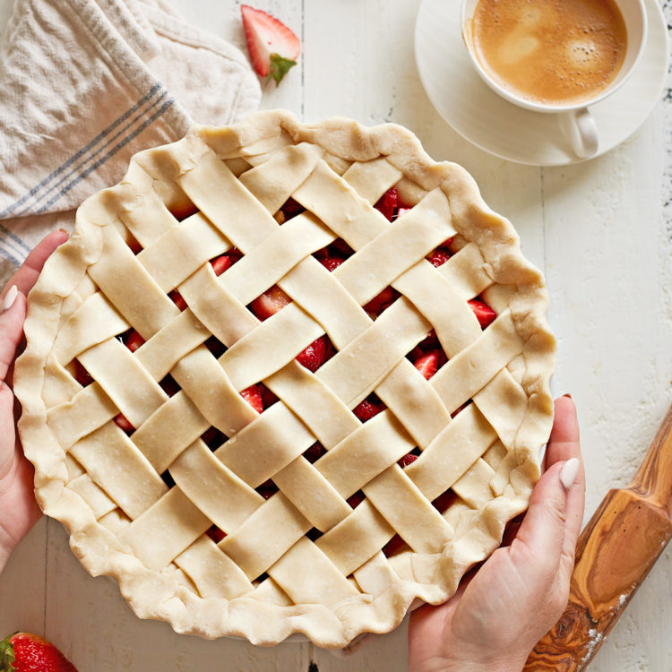 woman holding a pie with a lattice pie crust