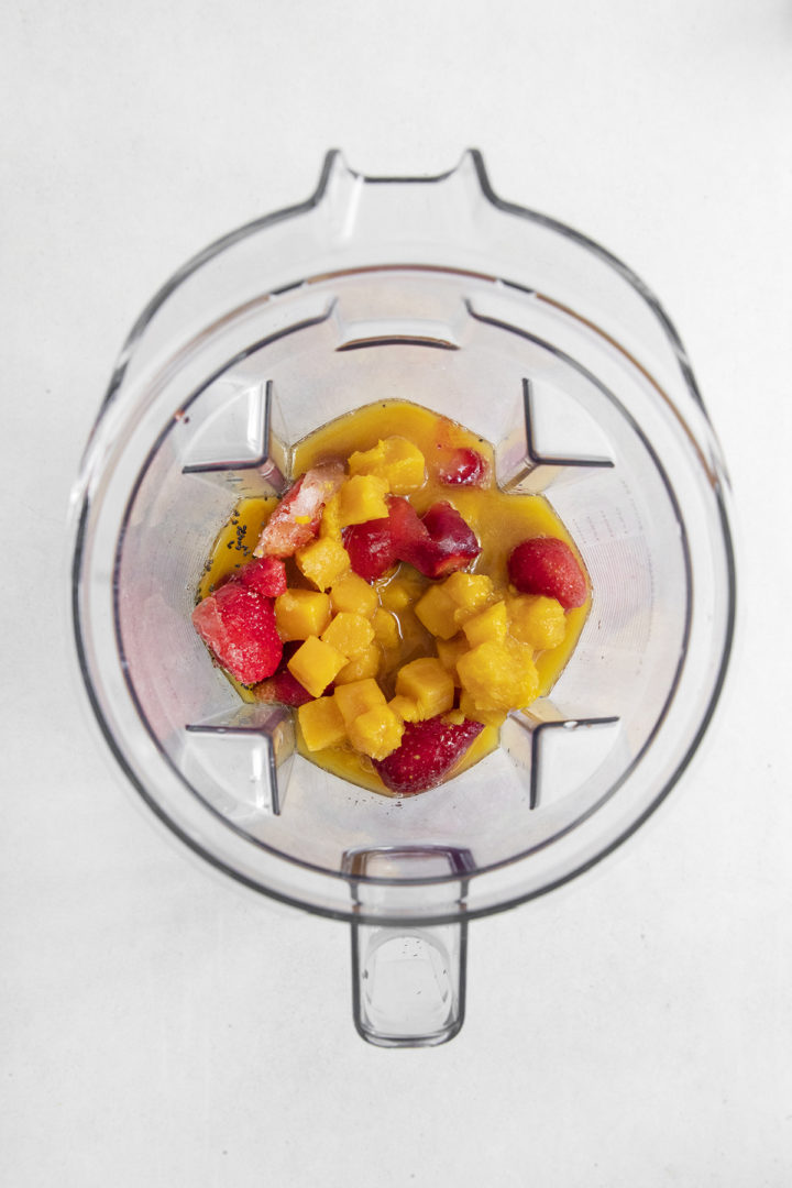 adding frozen passion fruit and frozen strawberries to the blender