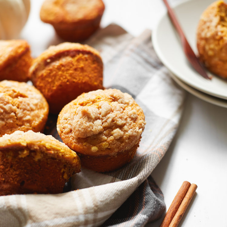 a batch of high protein pumpkin muffins on a plaid dish towel