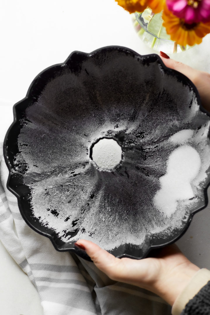 woman shaking sugar around a bundt pan to coat the inside