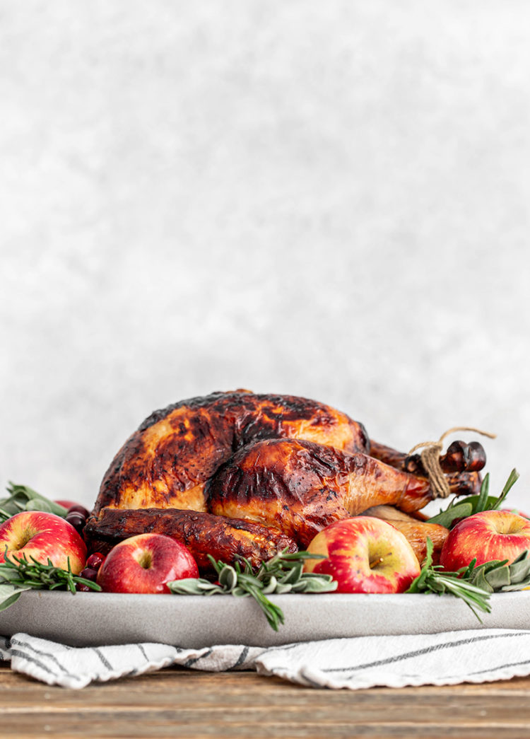 seasoned turkey on a platter surrounded by herbs