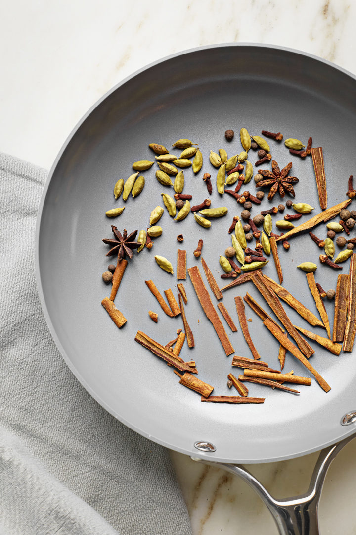 chai spices being toasted in a pan