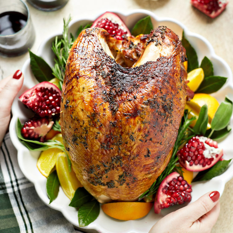 woman setting a platter of smoked turkey breast on the table