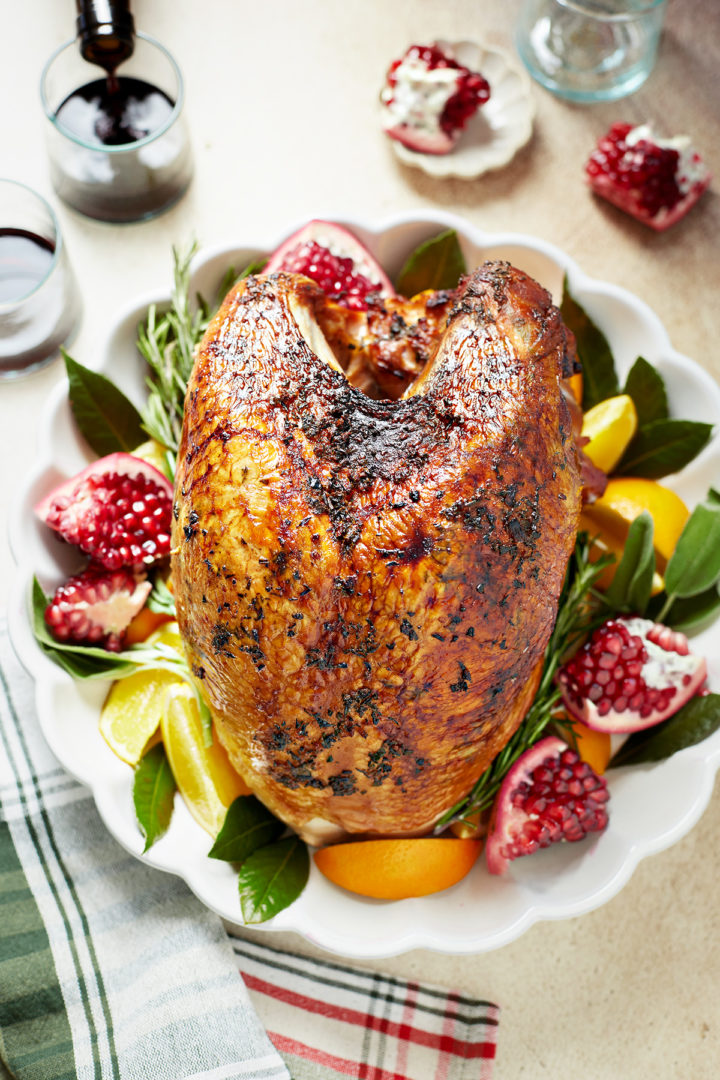 roasted turkey breast on a platter surrounded by fruit and herbs