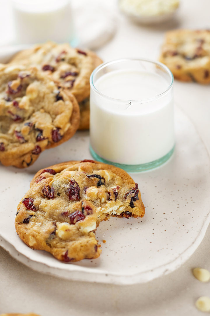 a glass of milk with a cranberry white chocolate cookie