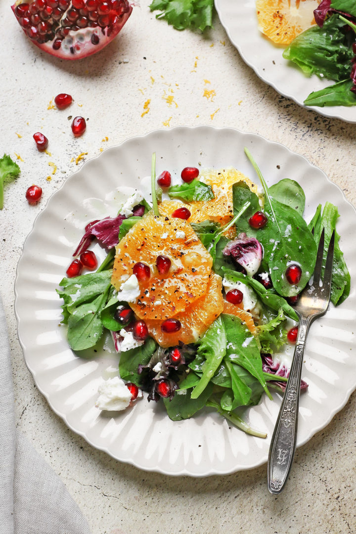 a plate of winter citrus salad with a fork and salad dressing