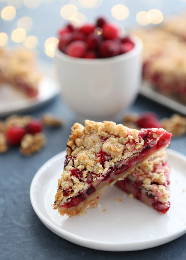 cranberry walnut bars on a white plate surrounded by christmas lights