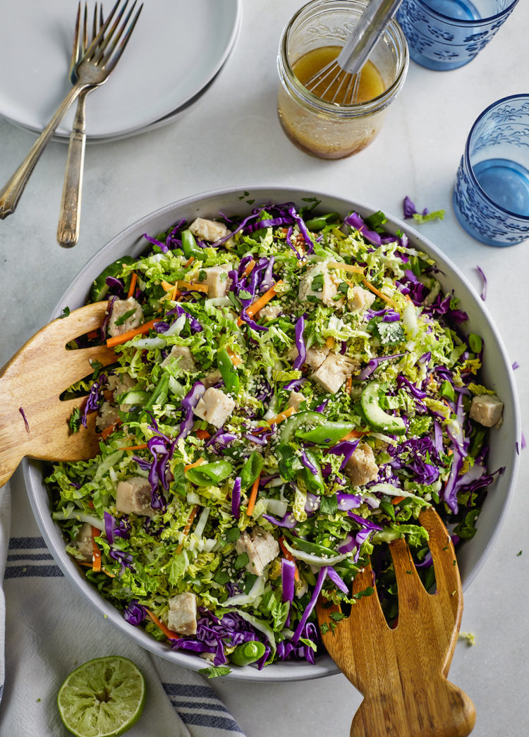 overhead photo bowl of asian chicken salad with wooden salad tongs