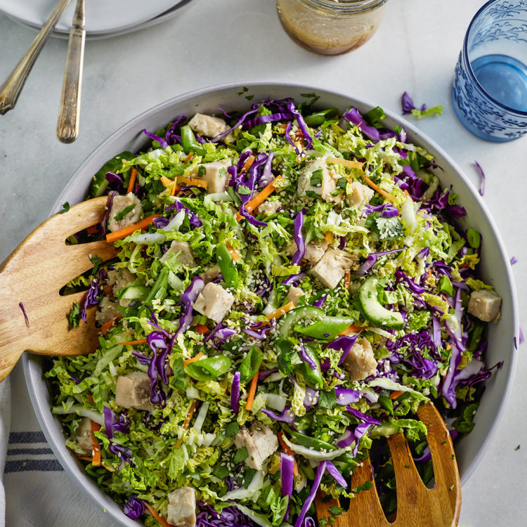 overhead photo bowl of asian chicken salad with wooden salad tongs