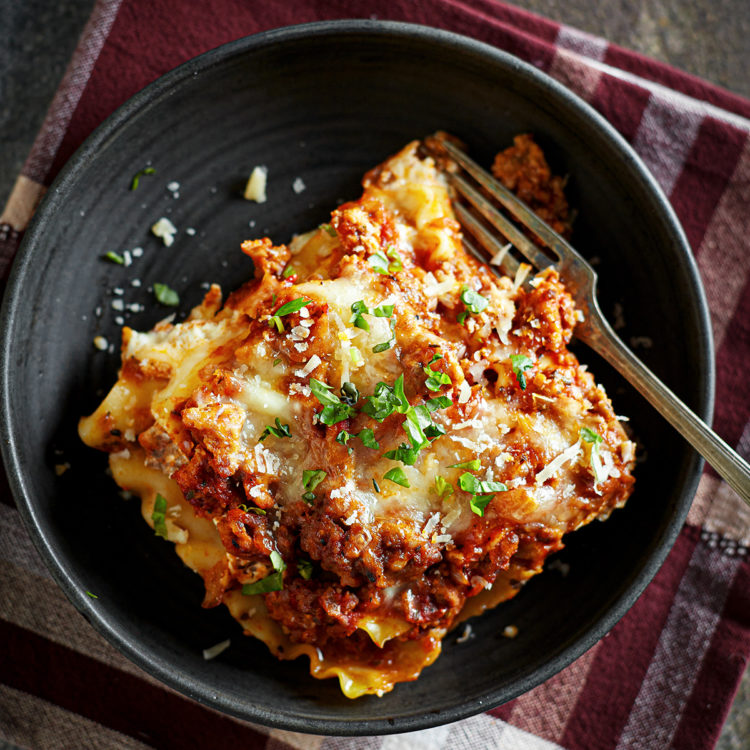 a slice of ground turkey lasagna on a black plate