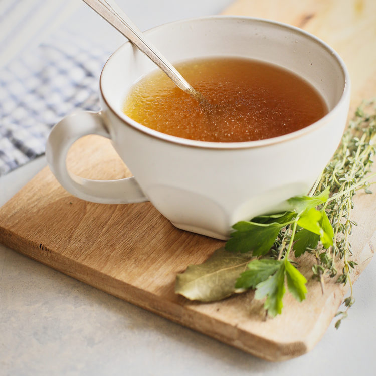 instant pot chicken stock in a white mug