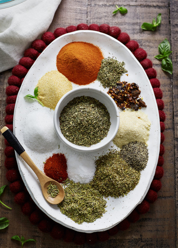 Overhead photo of homemade spaghetti seasoning ingredients arranged on a white oval plate