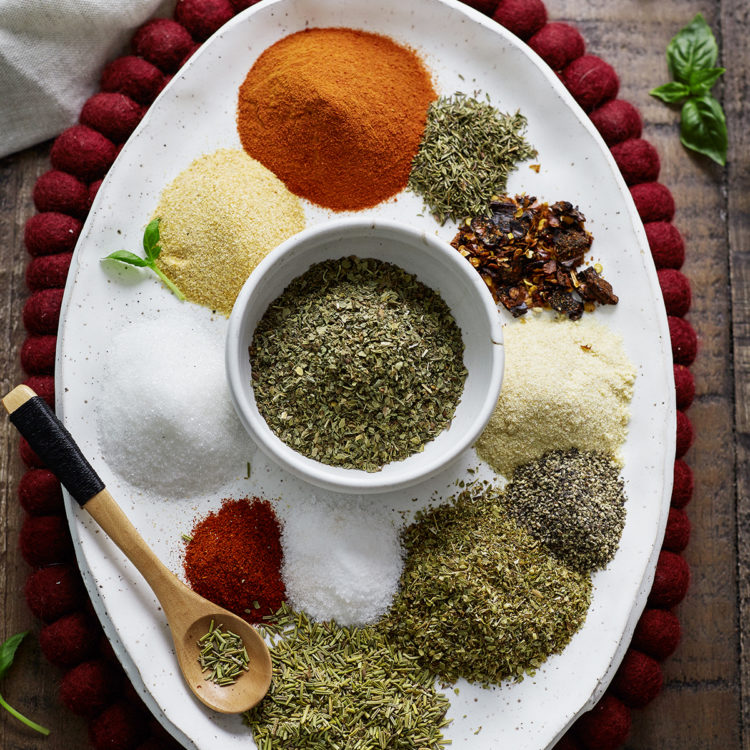 Overhead photo of homemade spaghetti seasoning ingredients arranged on a white oval plate