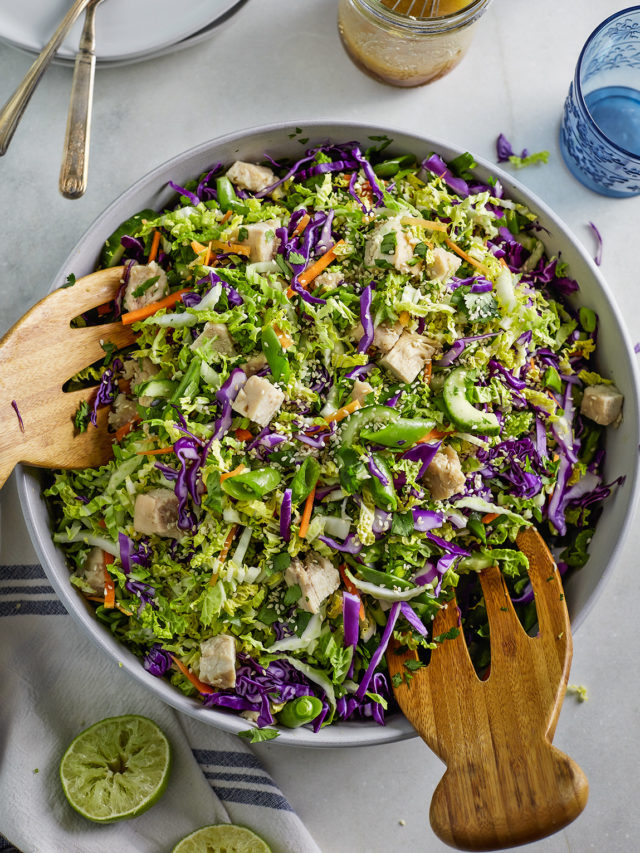 overhead photo bowl of asian chicken salad with wooden salad tongs