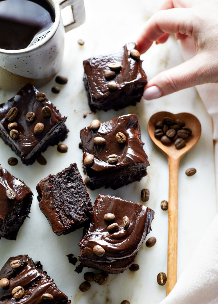 woman picking up an espresso brownie off a marble counter