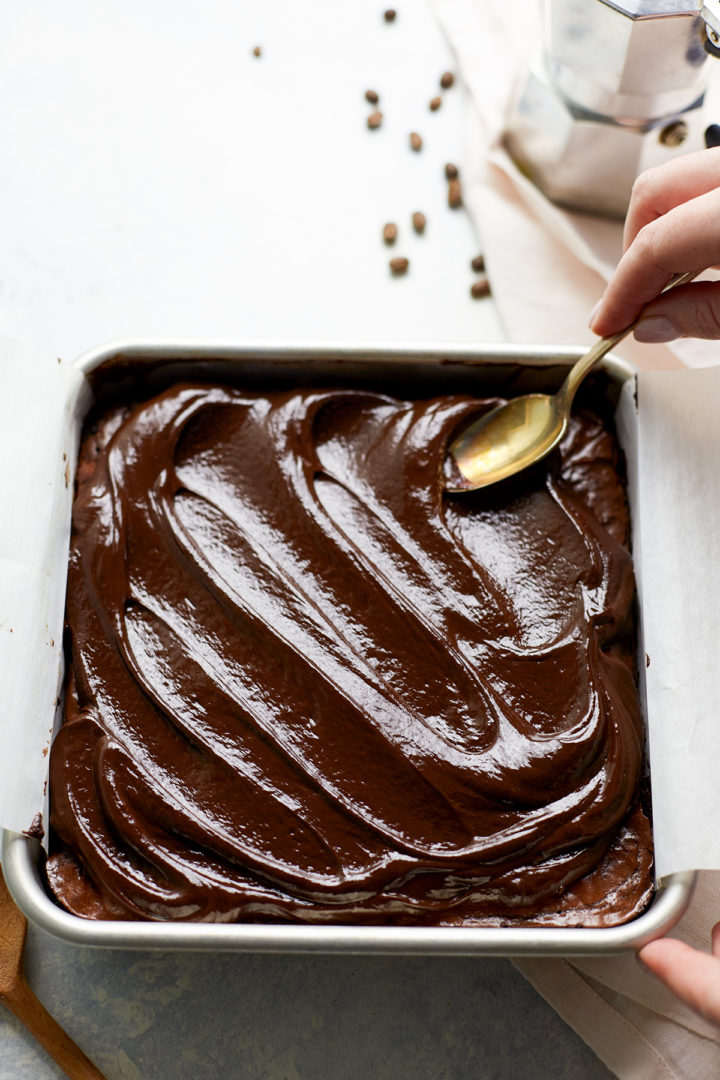 woman spreading ganache topping on brownies