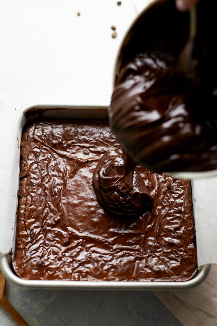 woman adding chocolate ganache on top of brownies