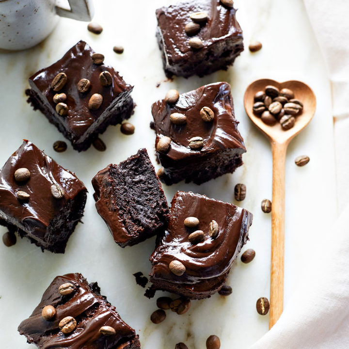 squares of espresso brownies topped with espresso beans on a marble counter