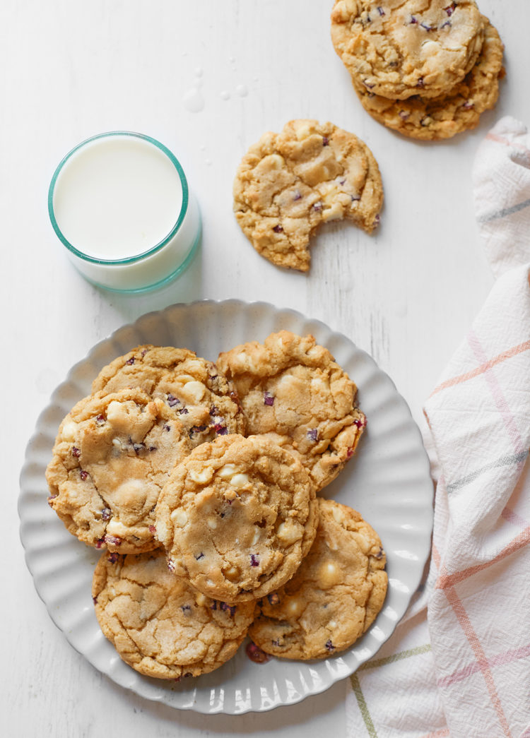 flat lay of a plate of blueberry cheesecake cookies with a glass of milk