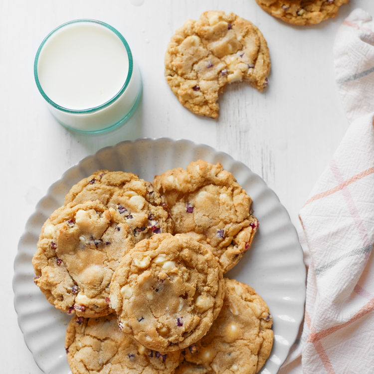 flat lay of a plate of blueberry cheesecake cookies with a glass of milk