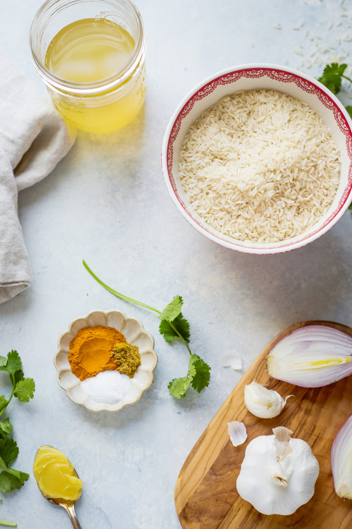 Ingredients for Instant Pot turmeric rice, featuring basmati rice, turmeric, cumin, chicken stock, ghee, with fresh cilantro for added freshness and flavor.